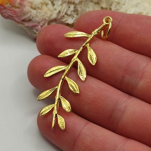 May include: Gold-toned metal pendant shaped like an olive branch with multiple leaves.