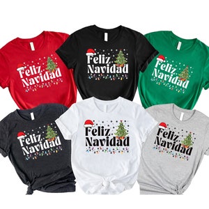 Peut inclure: Six t-shirts de différentes couleurs avec un sapin de Noël et le texte "Feliz Navidad" imprimé dessus.