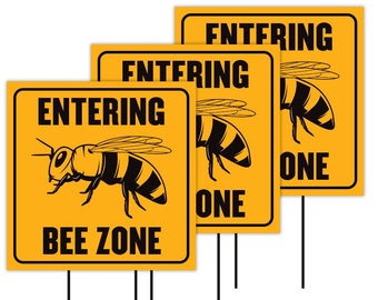 May include: Three yellow signs with black text and a bee graphic. The signs read "Entering Bee Zone".