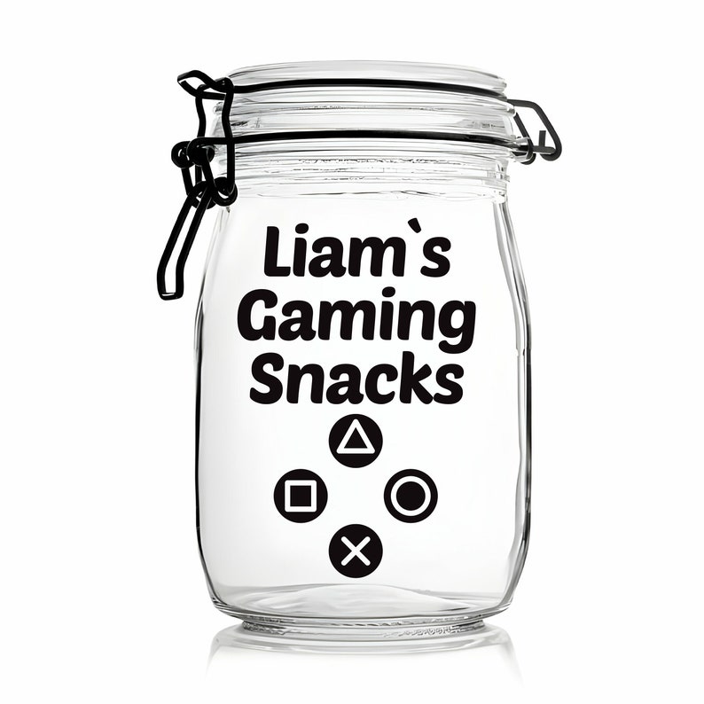 Peut inclure: Un pot en verre transparent avec un couvercle noir et une &eacute;tiquette qui dit "Liam's Gaming Snacks". L'&eacute;tiquette comporte &eacute;galement quatre symboles de manette noirs&nbsp;: un carr&eacute;, un cercle, un X et un triangle.