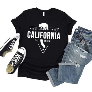 May include: Black t-shirt with a white graphic of a bear and a triangle with the text "CALIFORNIA Est. 1850" inside. The graphic also includes a star and the outline of the state of California.