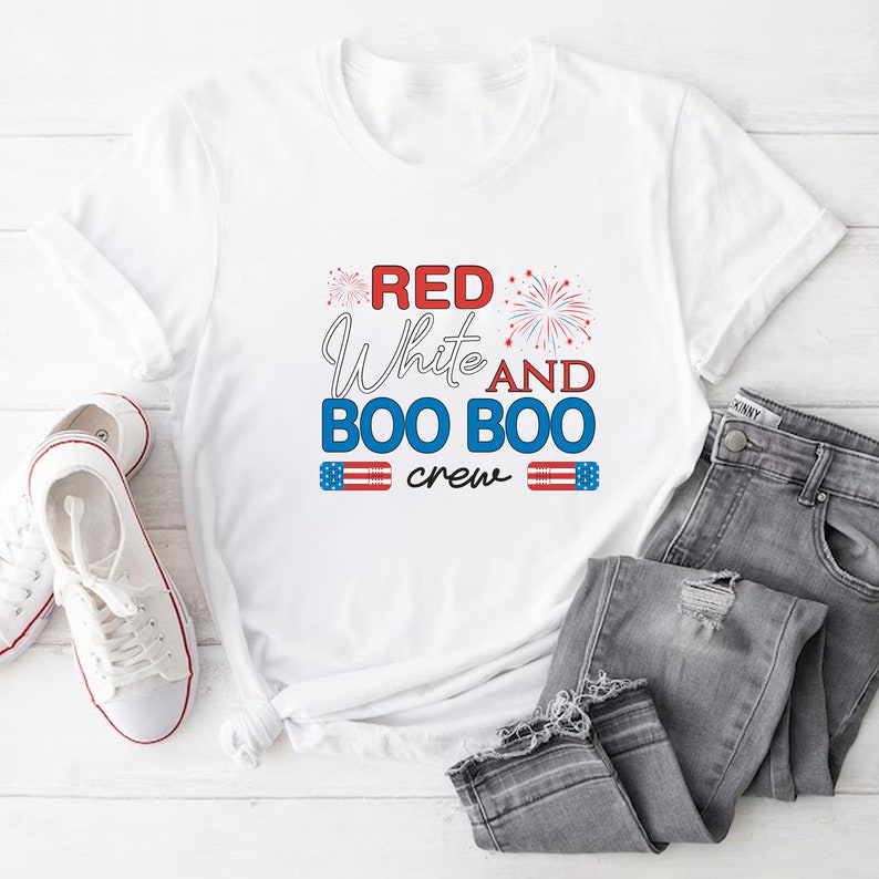 May include: White t-shirt with red, white, and blue text that reads "Red White and Boo Boo Crew" with firework graphics and American flag graphics.