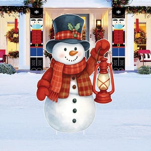 May include: A whimsical snowman yard decoration, holding a red lantern. The snowman wears a black top hat, a plaid scarf, and red mittens. The background shows a snowy scene with festive decorations, including nutcracker banners.