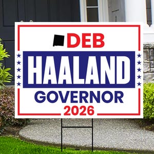 May include: A white yard sign with a red and blue border. The sign displays the name "DEB HAALAND" in large, bold letters, with the word "GOVERNOR" below and the year "2026" at the bottom. A black square and a star design are also present.