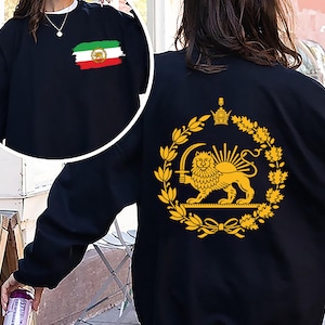 May include: Black sweatshirt with an Iranian flag design on the front and a gold emblem on the back. The emblem features a lion holding a sword, encircled by a wreath and crown. The sweatshirt has a crew neck.