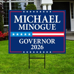 May include: A rectangular political yard sign with a dark blue background and a thin red border. The white text reads MICHAEL MINOGUE GOVERNOR 2026. A horizontal blue stripe with five white stars and a white stripe with a red line are in the center.