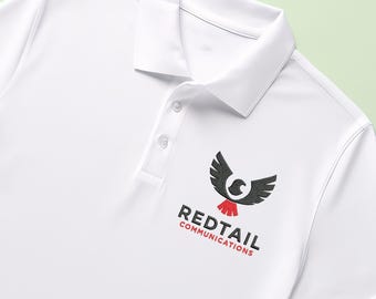 May include: A white polo shirt featuring a collar, a buttoned placket, and an embroidered logo on the chest. The logo depicts a black hawk with a red tail above the text REDTAIL COMMUNICATIONS in black and red lettering.