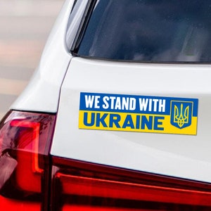 May include: A blue and yellow car sticker with the text "We Stand With Ukraine" and the Ukrainian coat of arms.