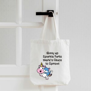 May include: White tote bag with a unicorn and a cat riding on its back. The bag has the text "Giddy up Sparkle Farts there's Chaos to Spread" printed on it.
