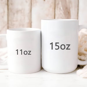 May include: Two white ceramic mugs with black text. The smaller mug is labeled "11oz" and the larger mug is labeled "15oz".
