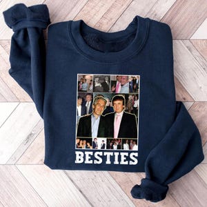 May include: Navy blue sweatshirt with a collage of photos and the word "BESTIES" in white. The collage features two men in suits. The sweatshirt is made of a soft material and has a crew neck.