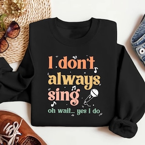 May include: Black sweatshirt with a colorful graphic that says "I don't always sing... oh wait... yes I do" with a microphone graphic.
