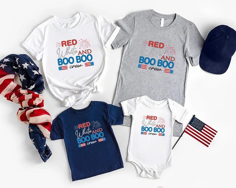 May include: A set of four shirts with the text "Red White and Boo Boo Crew" and a red, white, and blue firework graphic. The shirts are in white, gray, navy blue, and white. There is also a navy blue baseball cap and two American flags.