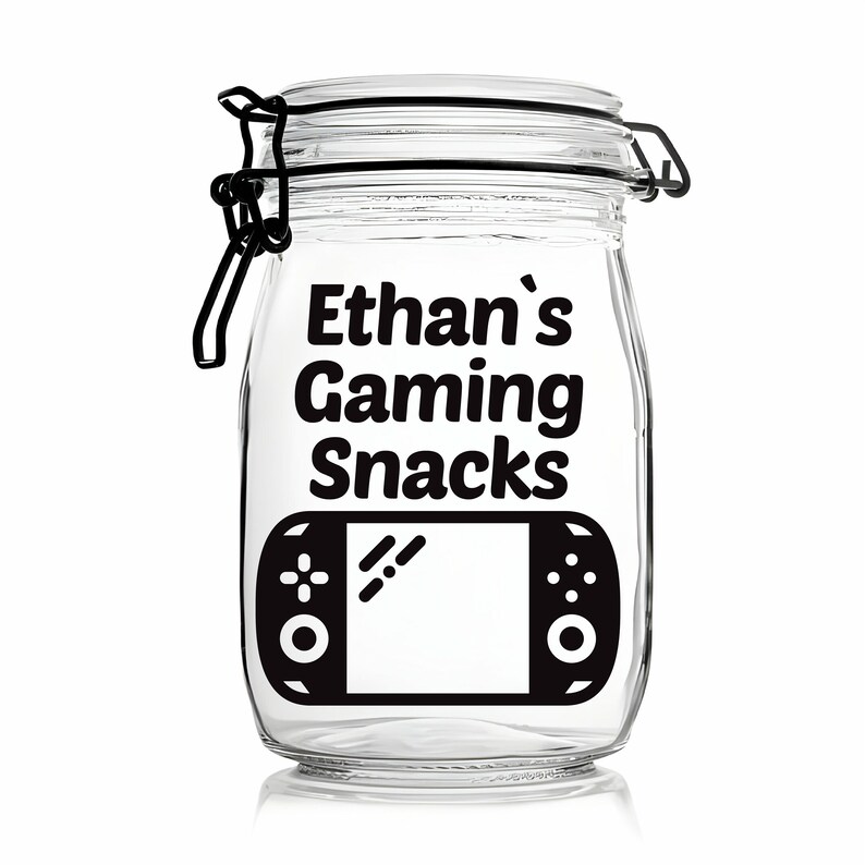 Peut inclure: Un pot en verre transparent avec un couvercle noir et une &eacute;tiquette noire sur laquelle est inscrit "Ethan's Gaming Snacks". L'&eacute;tiquette pr&eacute;sente &eacute;galement une illustration noir et blanc d'une manette de jeu vid&eacute;o.