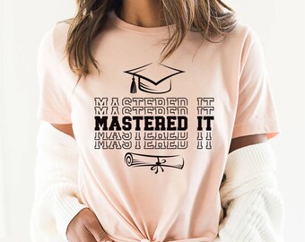 May include: A pink t-shirt with a black graduation cap and diploma graphic. The text "MASTERED IT" is repeated four times in a stacked design.