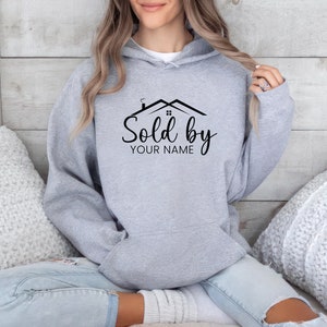 May include: Gray hooded sweatshirt with a black graphic of a house with the text "Sold by YOUR NAME".