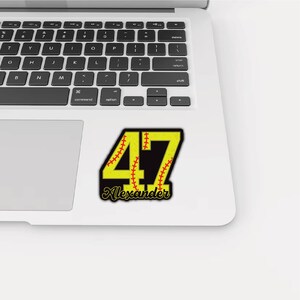 May include: A yellow and black sticker with the number 47 in a baseball design. The number is outlined in black with red stitching details. The name "Alexander" is written in cursive below the number.