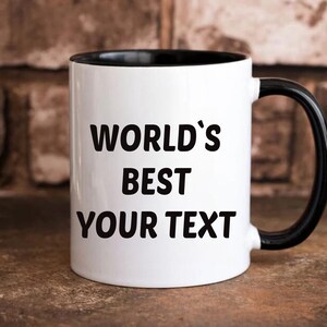 May include: White ceramic mug with a black rim and handle. The mug has black text that reads "WORLD'S BEST YOUR TEXT".