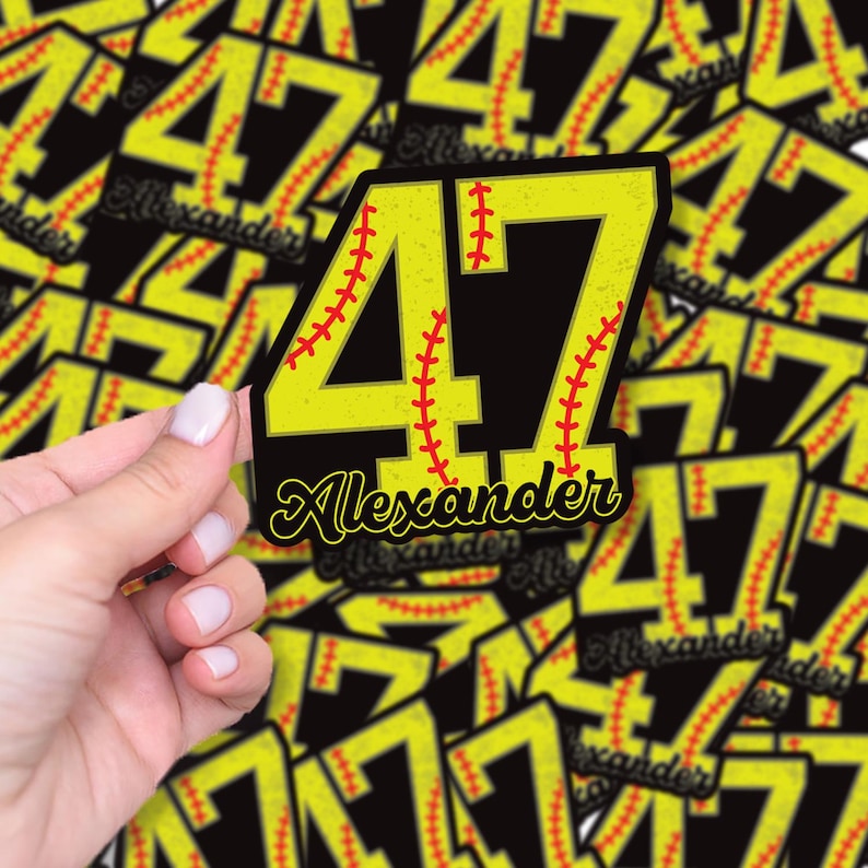 May include: A yellow and black sticker featuring the number 47 with red baseball stitching. The name "Alexander" is written in cursive below the number. The sticker is held by a hand, with other similar stickers in the background.