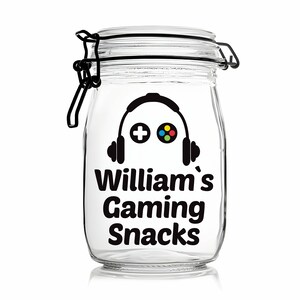 Peut inclure: Un pot en verre transparent avec un couvercle noir et un autocollant noir et blanc qui dit "William's Gaming Snacks". L'autocollant pr&eacute;sente &eacute;galement une silhouette noire d'une manette de jeu vid&eacute;o avec un casque.