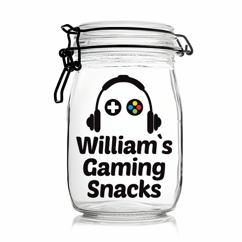 Peut inclure: Un pot en verre transparent avec un couvercle noir et un autocollant noir et blanc qui dit "William's Gaming Snacks". L'autocollant pr&eacute;sente &eacute;galement une silhouette noire d'une manette de jeu vid&eacute;o avec un casque.