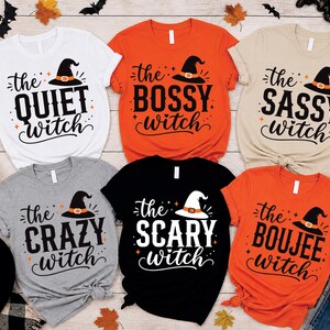 May include: Six short-sleeve t-shirts in white, orange, beige, gray, black, and bright orange. Each shirt features a witch hat graphic and text reading the quiet witch, the bossy witch, the sassy witch, the crazy witch, the scary witch, and the boujee witch.