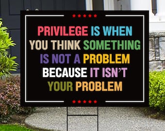 May include: A black and white yard sign with the text "PRIVILEGE IS WHEN YOU THINK SOMETHING IS NOT A PROBLEM BECAUSE IT ISN'T YOUR PROBLEM" in rainbow colors.