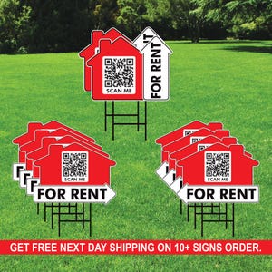 May include: A set of red and white 'For Rent' real estate signs with a QR code that says 'Scan Me'. The signs are on stakes and are displayed on a grassy lawn.