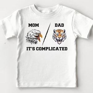 May include: White t-shirt with a black eagle and tiger graphic and the text "Mom Dad It's Complicated".