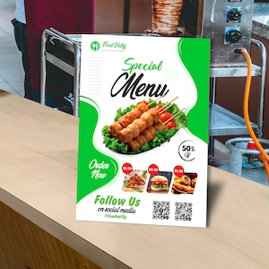 May include: A green and white flyer with the text "Food Valliy" and "Special Menu". The flyer features a photo of a skewer of grilled food with a green background. The flyer also includes the text "Order Now" and "Follow Us on social media @foodvalliy".