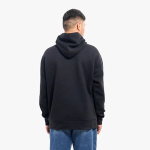 May include: A black hooded sweatshirt with a drawstring hood. The sweatshirt has long sleeves and a kangaroo pocket.