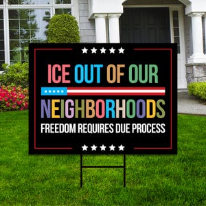May include: A black yard sign with the text "ICE OUT OF OUR NEIGHBORHOODS FREEDOM REQUIRES DUE PROCESS" in various colors. The sign has a red border and white stars. It is placed on a green lawn.