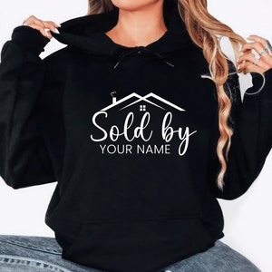 May include: Black hooded sweatshirt with a white graphic of a house with the text "Sold by YOUR NAME".