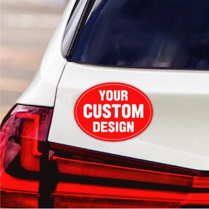 May include: A red oval sticker with white text that reads "YOUR CUSTOM DESIGN" on a white car.