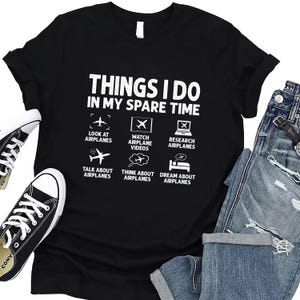 May include: Black t-shirt with white text that reads "Things I do in my spare time". The text is surrounded by six icons depicting aeroplanes, aeroplane videos, researching aeroplanes, talking about aeroplanes, thinking about aeroplanes, and dreaming about aeroplanes.