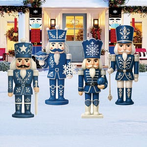 May include: Four blue and white decorative nutcrackers with various accessories, including a sword, snowflake, and orb. The nutcrackers are standing in front of a house decorated for the holidays.