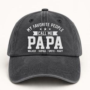 May include: A dark gray baseball cap with the text "MY FAVORITE PEOPLE CALL ME PAPA" in white. Below the word "PAPA" are the names WALKER, SOPHIA, SMITH, and MARY. The cap has a curved brim and a button on top.