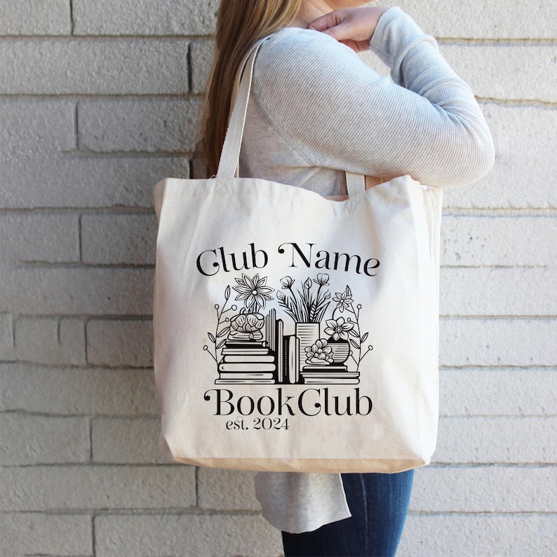 Puede incluir: Una bolsa de lona blanca con texto negro y un gr&aacute;fico de libros apilados y flores. El texto dice "Club Name Book Club est. 2024".