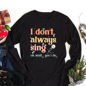 May include: Black long-sleeve shirt with the text "I don't always sing oh wait... yes I do" in colorful letters with a microphone graphic.
