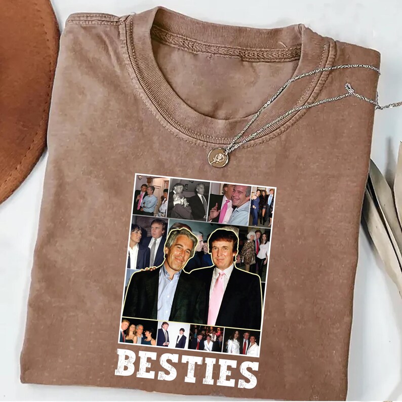 May include: A brown t-shirt with a collage of photos and the word "BESTIES" in white. A silver necklace with a pendant is draped on the shirt. The collage features two men in suits.