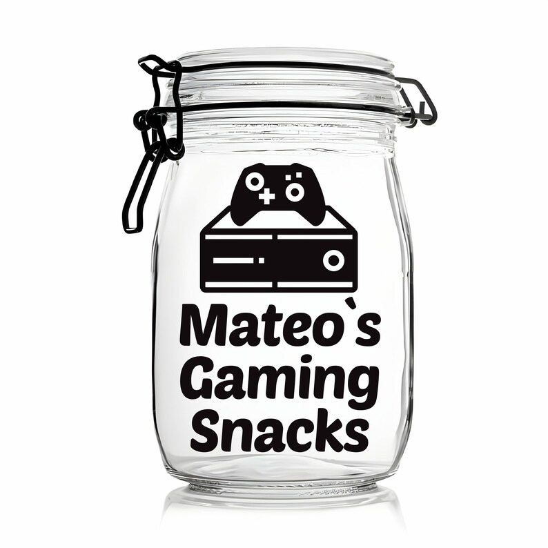 Peut inclure: Un pot en verre transparent avec un autocollant noir et blanc qui dit "Mateo's Gaming Snacks". L'autocollant repr&eacute;sente &eacute;galement une manette de jeu vid&eacute;o et une console.
