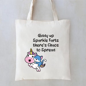 May include: A white tote bag with a black and white cartoon unicorn and a blue cat. The text on the bag reads "Giddy up Sparkle Farts there's Chaos to Spread".