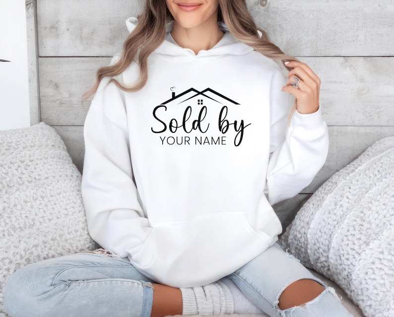 May include: White hooded sweatshirt with a black graphic of a house with the text "Sold by YOUR NAME" printed on the front.