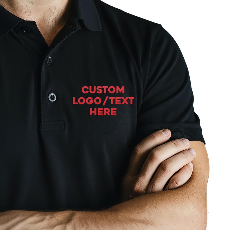 May include: Black polo shirt with short sleeves and a button-down collar. The shirt features the text "CUSTOM LOGO/TEXT HERE" in red on the chest. The person's arms are crossed.