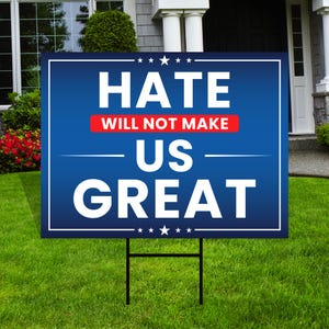 May include: A blue and white yard sign with the text "Hate Will Not Make Us Great" in white letters. The words "Will Not Make" are in a red rectangle.