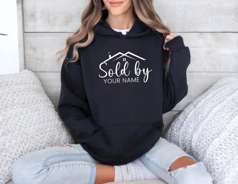 May include: Black hooded sweatshirt with a white graphic of a house with the text "Sold by YOUR NAME" printed on the front.
