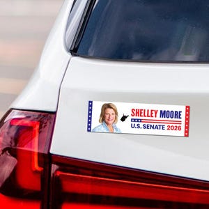 May include: A rectangular bumper sticker featuring Shelley Moore, the text "SHELLEY MOORE U.S. SENATE 2026", and a West Virginia outline. The sticker has blue and red accents and is attached to a white car.