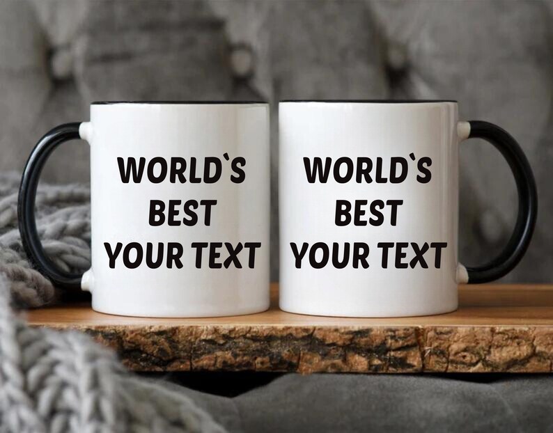 May include: Two white ceramic mugs with black handles and black rims. The mugs have the text "World's Best" and "Your Text" printed on them.