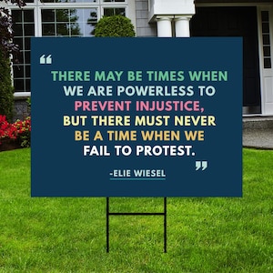 May include: A blue yard sign with a quote by Elie Wiesel: "There may be times when we are powerless to prevent injustice, but there must never be a time when we fail to protest."