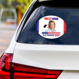 May include: Oval sticker on a car window with Shelley Moore's portrait, the outline of West Virginia, and the text "U.S. Senate 2026." The sticker has a white background with blue and red borders.